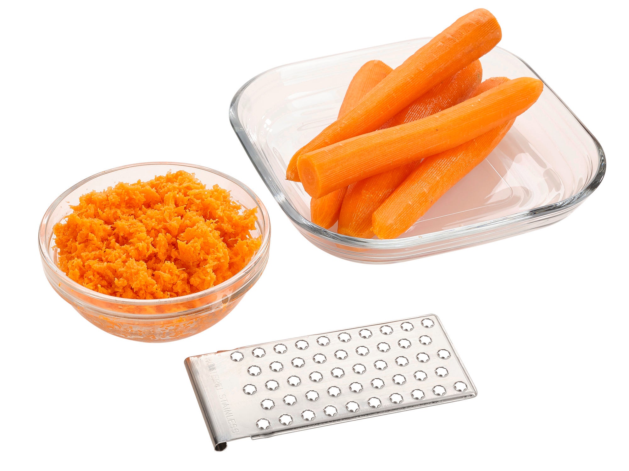 Une râpe universelle est posée à côté d'un bol en verre contenant des carottes râpées et d'un autre bol contenant des carottes entières. Idéale pour râper les légumes.