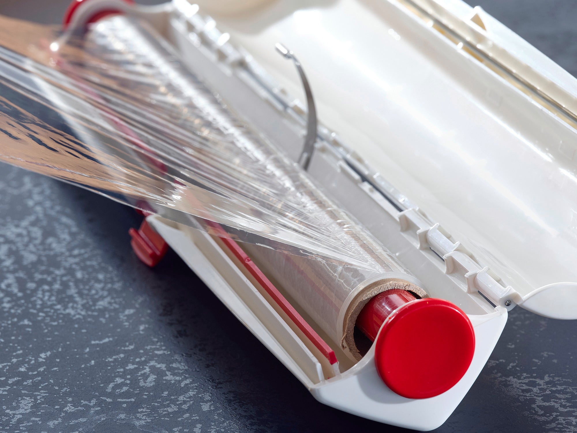 Folienschneider Perfect Cut in Anwendung: Der Folienschneider mit rotem Griff schneidet präzise Frischhaltefolie. Ideal für sauberes und einfaches Abtrennen.