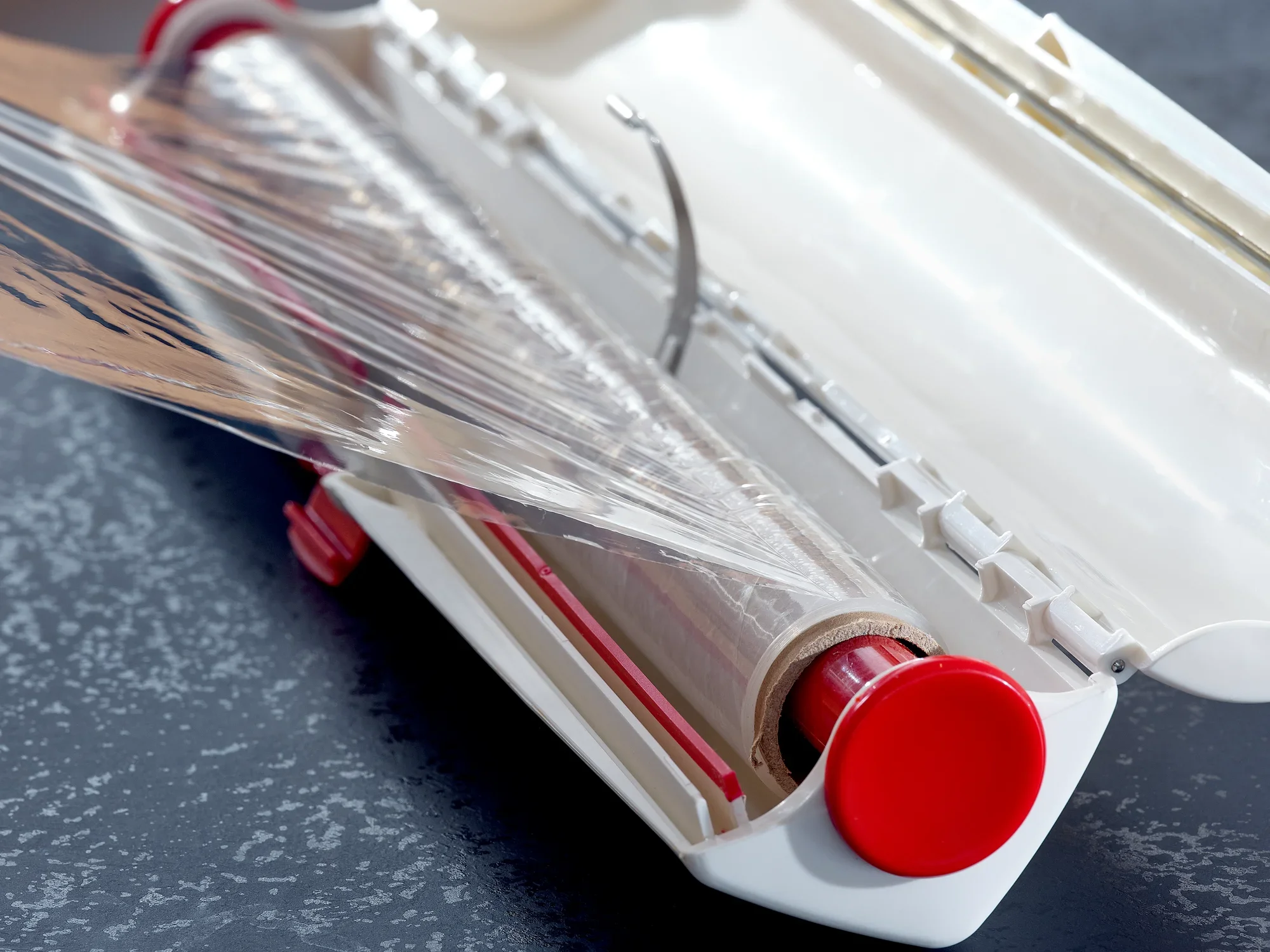 Perfect Cut foil cutter in use: The foil cutter with a red handle cuts cling film precisely. Ideal for clean and easy cutting.