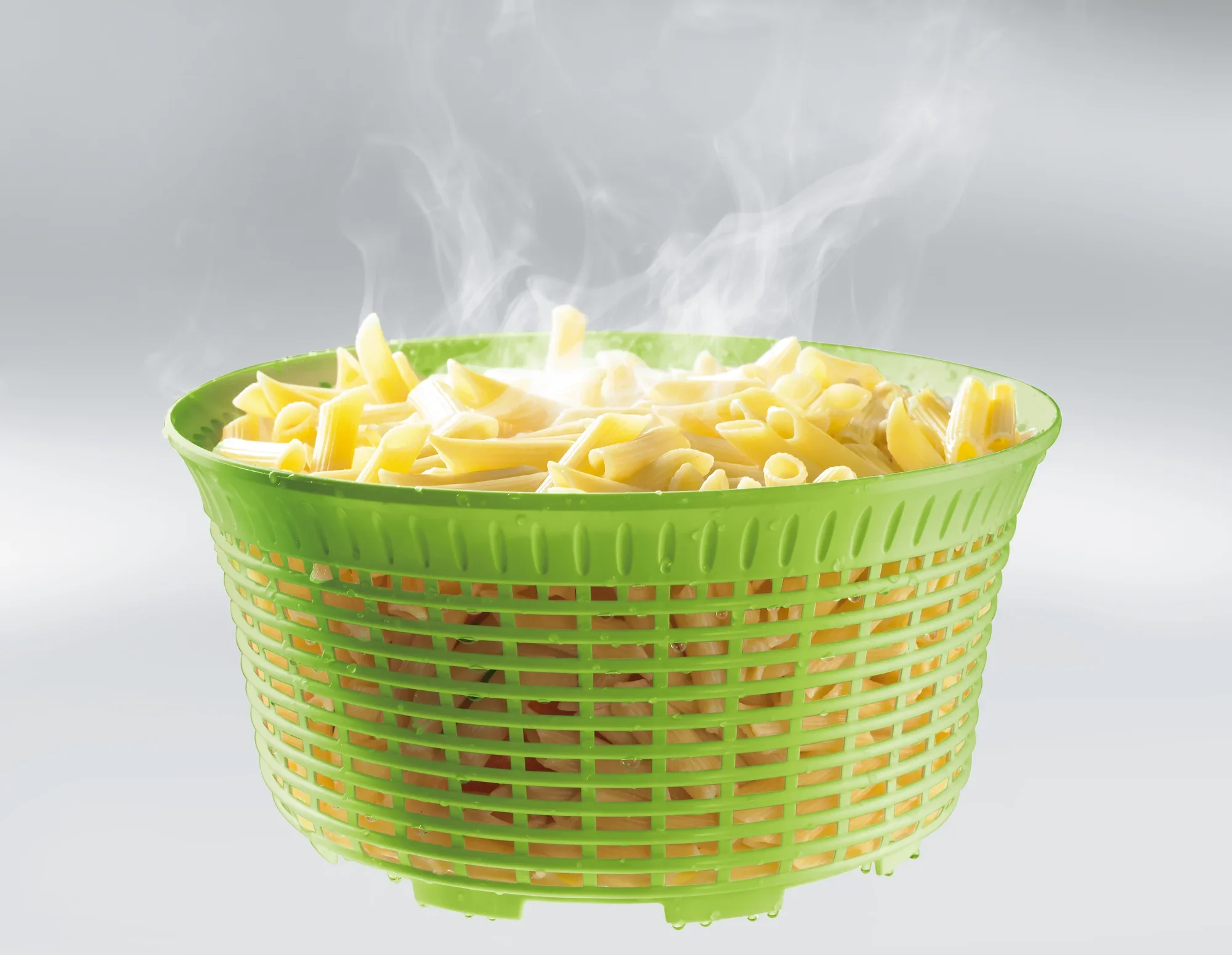 Zielona wirówka do sałaty o pojemności 5,5 litra, wypełniona parującym makaronem. Idealny do odcedzania i suszenia sałaty lub makaronu.