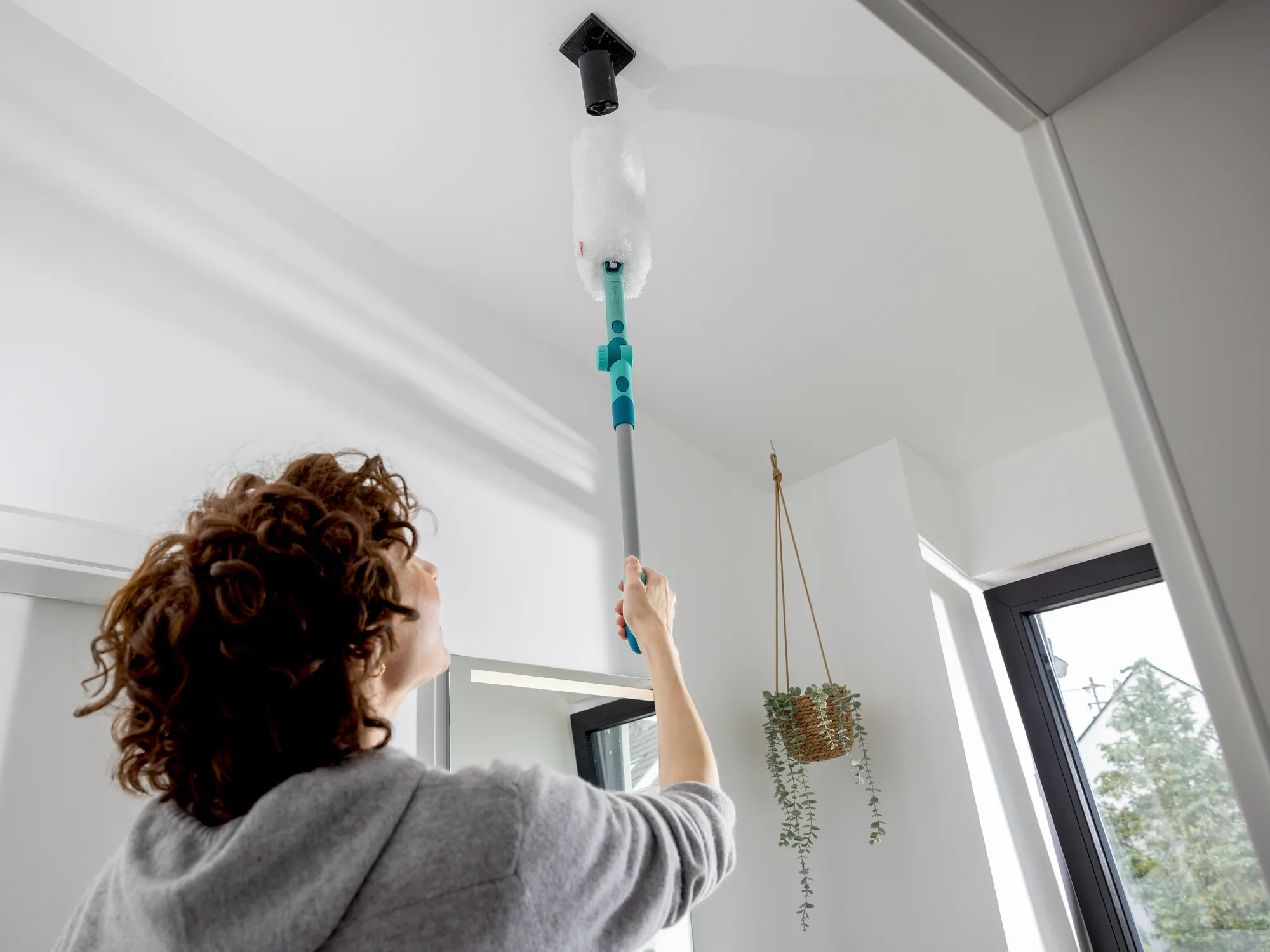 Eén persoon gebruikt de SUPERDUSTER XL Pro Reach om een hoog plafond schoon te maken. De plumeau bereikt moeiteloos de moeilijk bereikbare plaatsen en zorgt voor netheid.