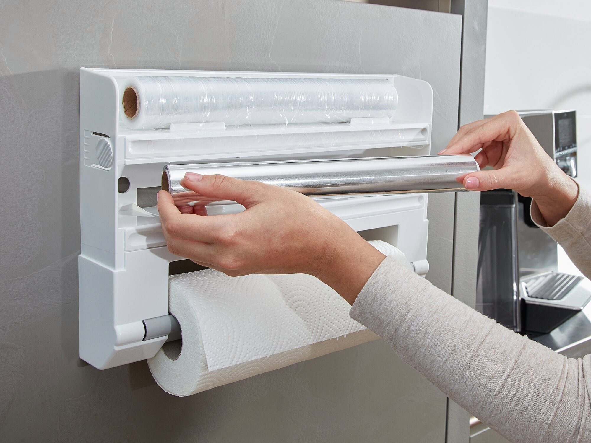 Wandrollenhalter Parat an einer Küchenwand montiert. Eine Person wechselt die Aluminiumfolie. Der Halter bietet Platz für Folien und Küchenpapier, praktisch und platzsparend.