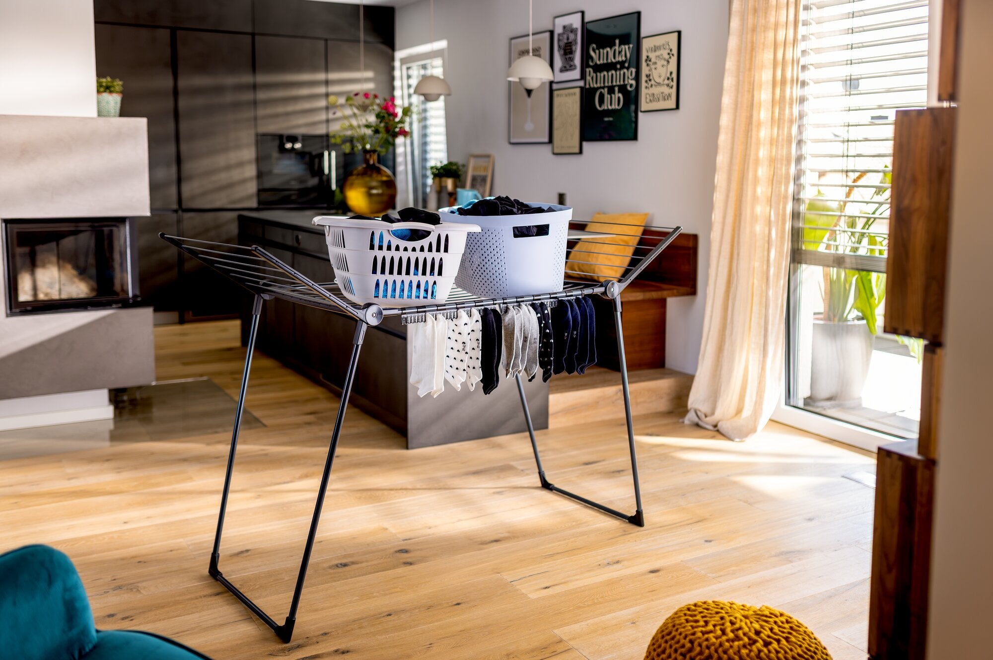 Étendoir à linge Leifheit Pegasus Family 18 m noir, posé dans un salon lumineux avec cadre noir et barres de séchage foncées, supportant du linge et des paniers, présenté comme un étendoir intérieur spacieux et autonome.