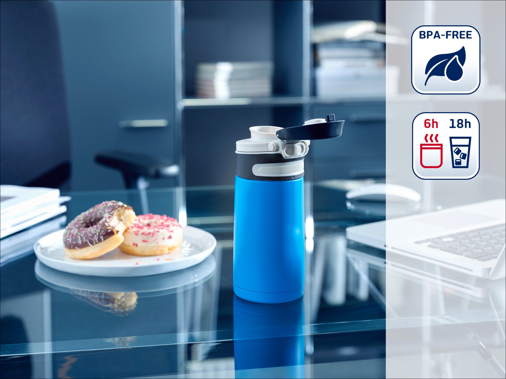 Een blauwe thermosfles staat op een moderne kantoortafel naast een bord donuts. De fles is BPA-vrij en houdt drankjes 6 uur warm en 18 uur koud.
