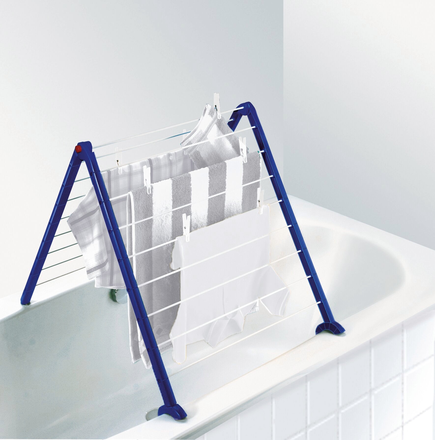 Ein Badewannentrockner Pegasus Bath 110 ist über einer Badewanne aufgestellt. Der Trockner hat blaue Beine und weiße Leinen, auf denen Handtücher hängen. Ideal für kleine Räume.