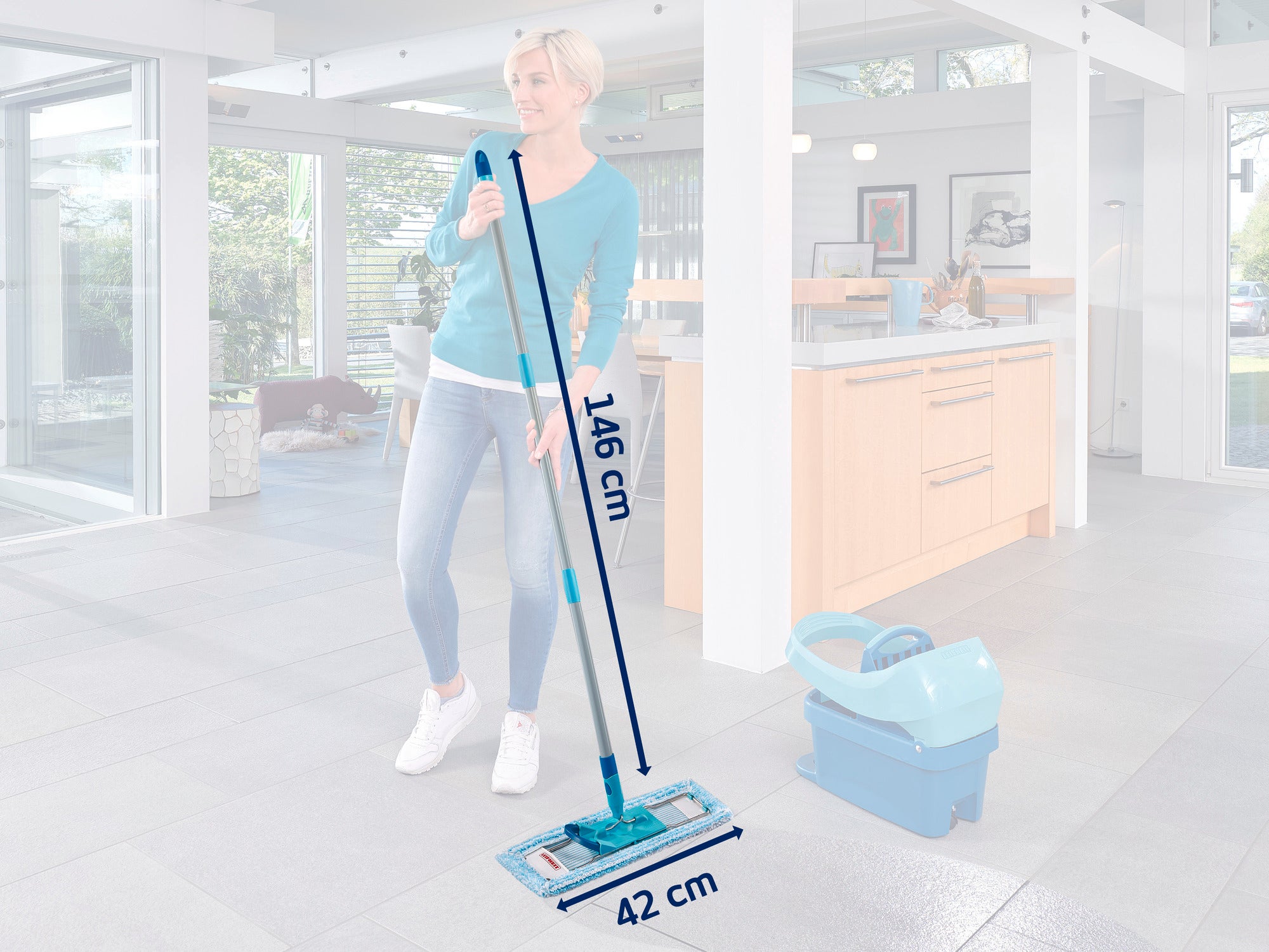 Kobieta myje podłogę w nowoczesnej kuchni za pomocą mopa Leifheit. Mop ma długość 146 cm i szerokość 42 cm. W tle widać duże okna i jasne meble.