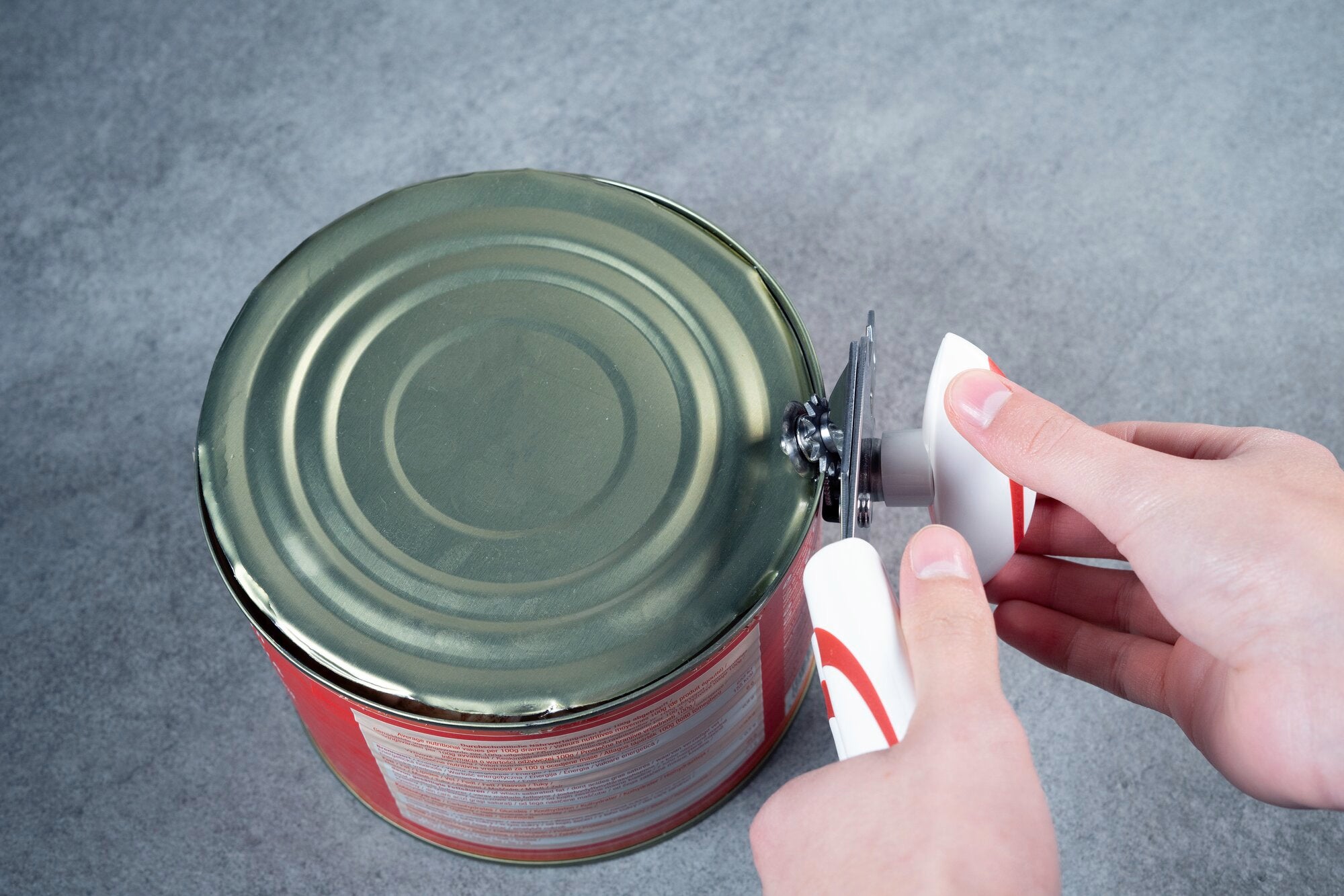 Dosenöffner Lifty im Einsatz: Eine Hand hält den ergonomischen Griff des Lifty, während die Klinge mühelos den Deckel einer großen Konservendose öffnet. Ideal für den täglichen Gebrauch.