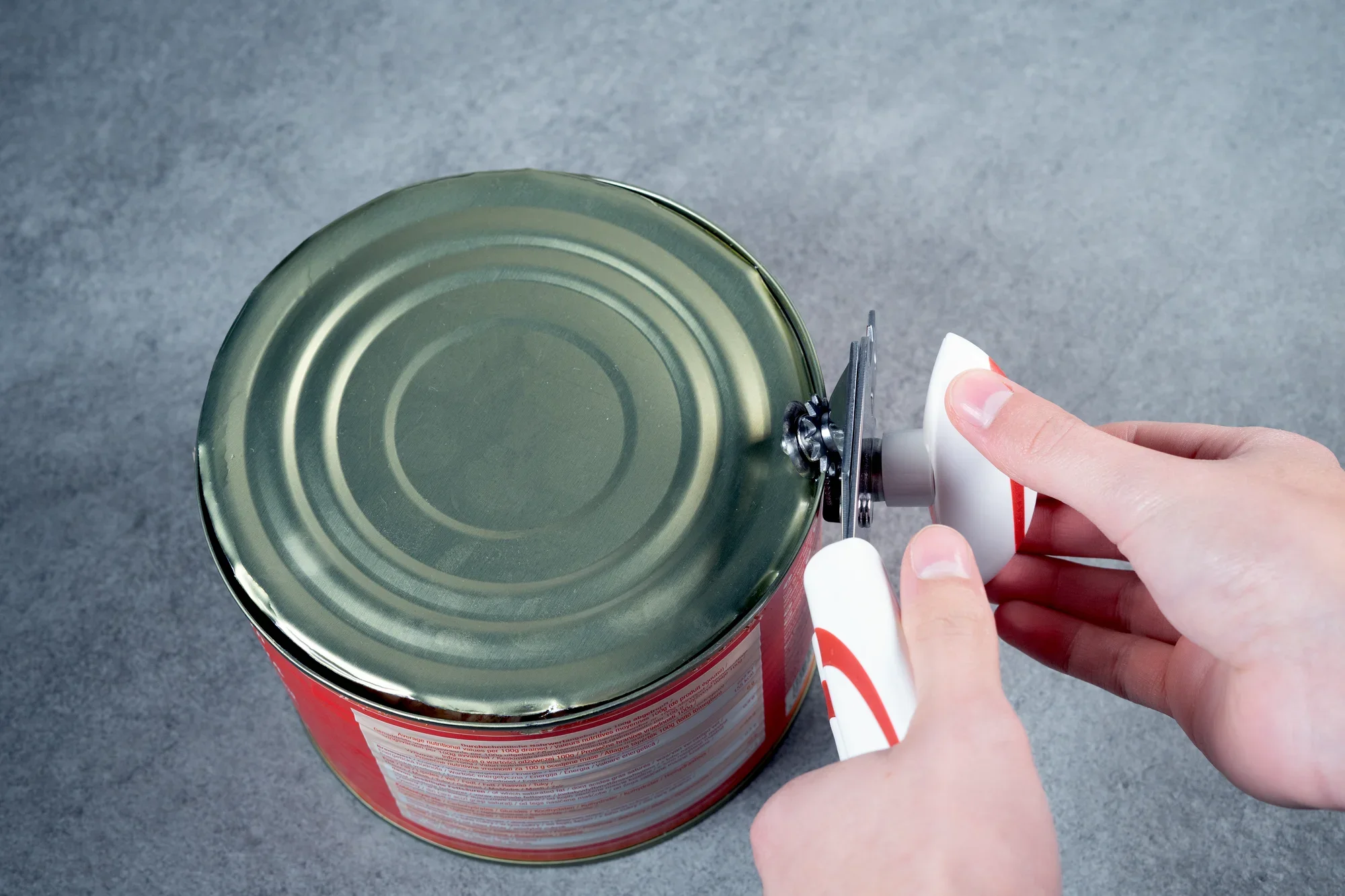 Dosenöffner Lifty im Einsatz: Eine Hand hält den ergonomischen Griff des Lifty, während die Klinge mühelos den Deckel einer großen Konservendose öffnet. Ideal für den täglichen Gebrauch.