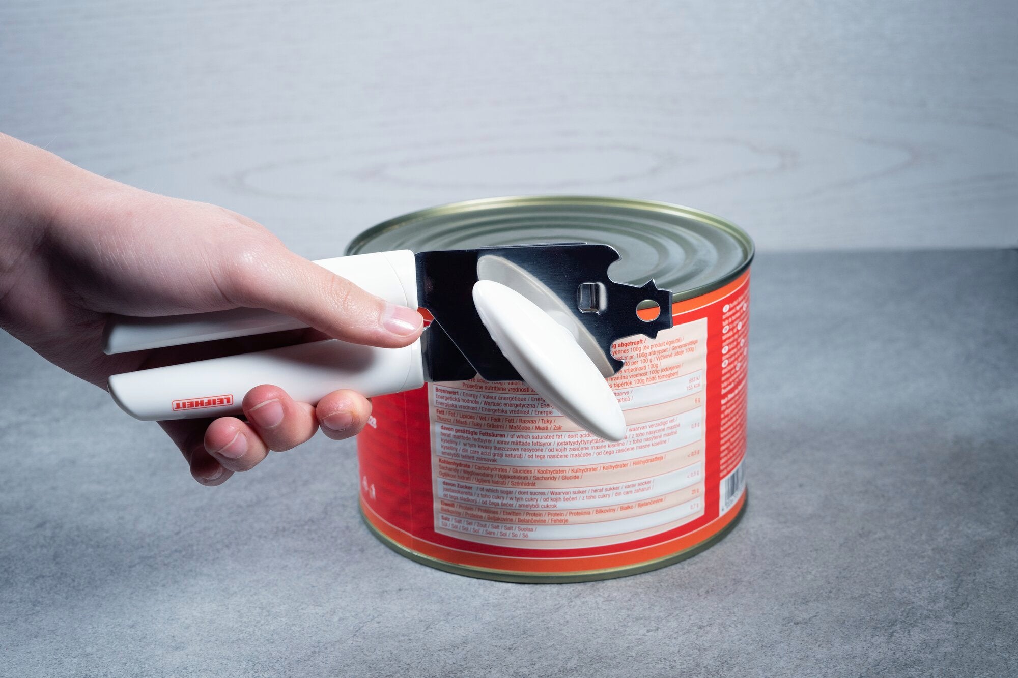 Eén hand gebruikt de Exact blikopener om een groot blik te openen. De ergonomische handgreep en het precieze lemmet maken het openen gemakkelijker.