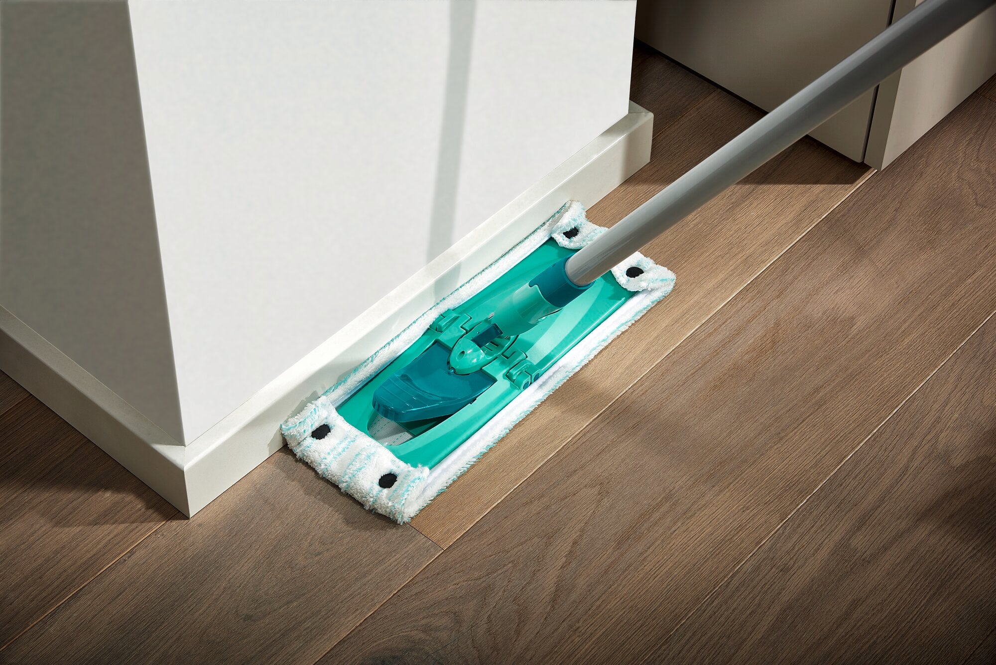 Een Combi M serie vloerwisser wordt gebruikt om de vloer langs een muur schoon te maken. De mop heeft een plat, rechthoekig ontwerp en is ideaal voor hoeken.