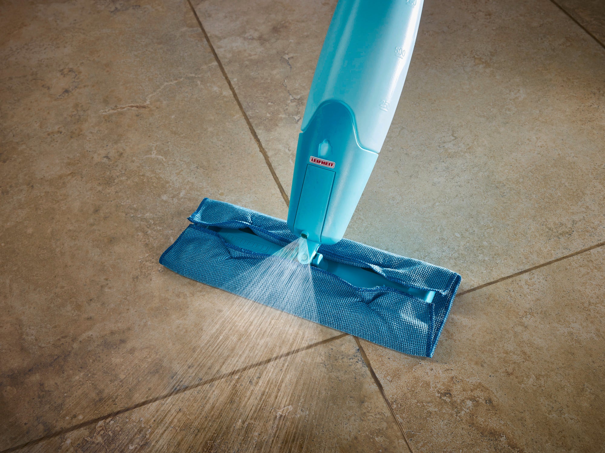 Ein Sprühwischer Pico Spray wird auf einem Fliesenboden verwendet. Der Wischer hat einen blauen Reinigungskopf, der Wasser gleichmäßig auf die Oberfläche sprüht. Ideal für eine gründliche und einfache Reinigung.