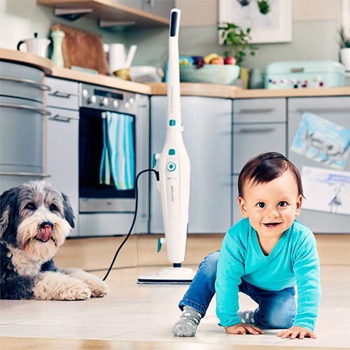 Un bebe souriant en pull bleu rampe sur le sol d'une cuisine moderne, a c