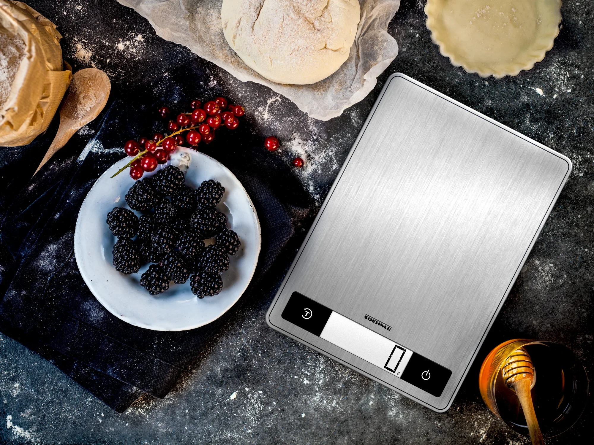Digitale Küchenwaage Page Profi 200 auf einer Arbeitsfläche mit Zutaten wie Mehl, Brombeeren und Honig. Ideal für präzises Abwiegen beim Backen und Kochen.