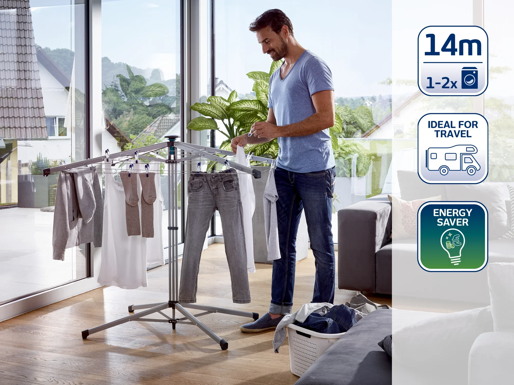 Un hombre está de pie en una moderna sala de estar y utiliza un tendedero para secar la ropa. El tendedero es compacto y perfecto para viajar. Ahorra energía y ofrece espacio para hasta 14 metros de ropa.