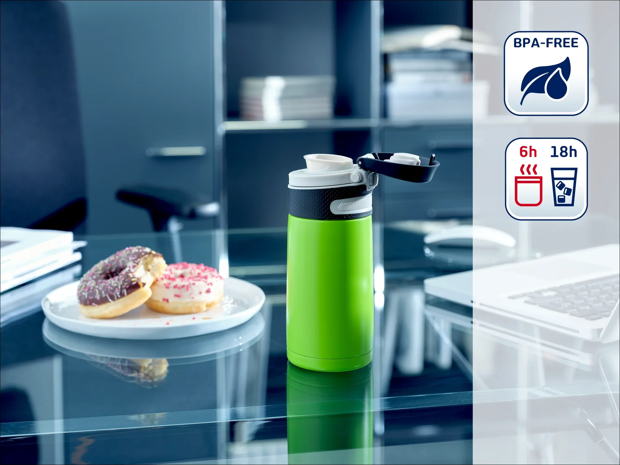 Zielony termos stoi na szklanym stole w biurze. Obok leżą dwa pączki na talerzu. Butelka jest wolna od BPA i utrzymuje temperaturę napojów przez 6 godzin, a zimno przez 18 godzin.