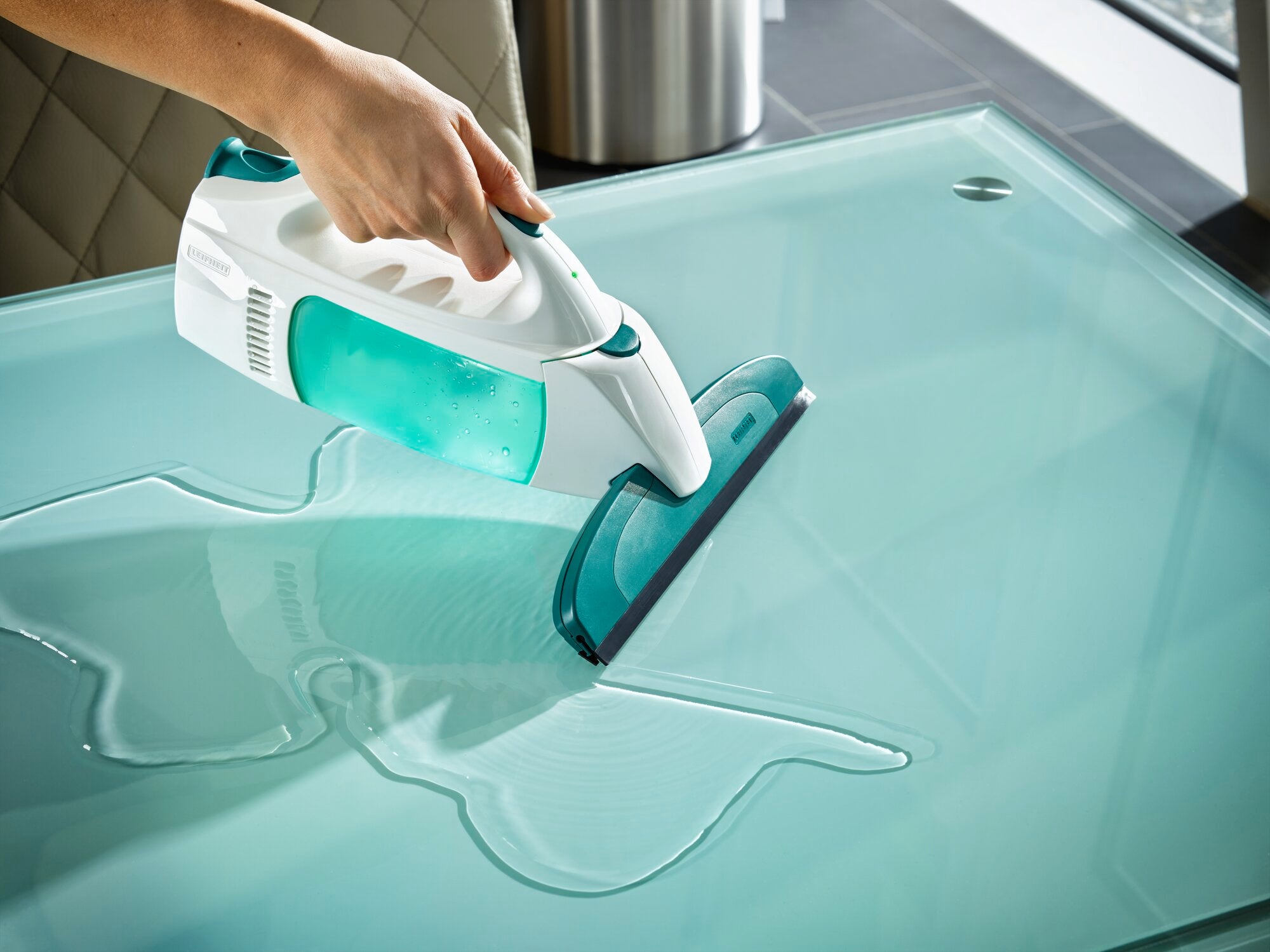Ein Fenstersauger namens "Dry and Clean" wird verwendet, um eine Glasoberfläche zu reinigen. Das Gerät entfernt effektiv Wasser und hinterlässt eine streifenfreie Fläche.