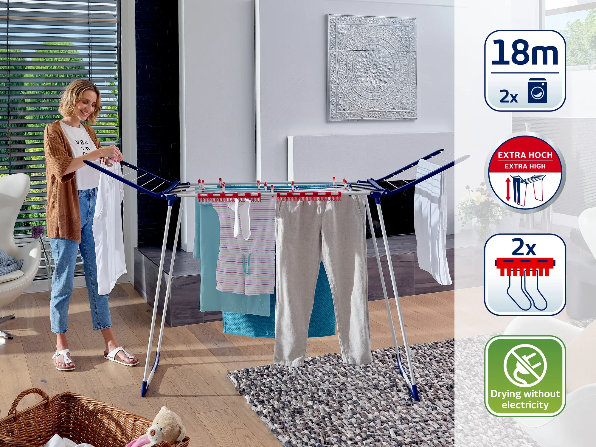 Eine Frau hängt Wäsche auf einem Standtrockner auf. Der Trockner bietet 18 Meter Trockenlänge, ist extra hoch und ermöglicht das Trocknen ohne Strom. Ideal für den Innenbereich.
