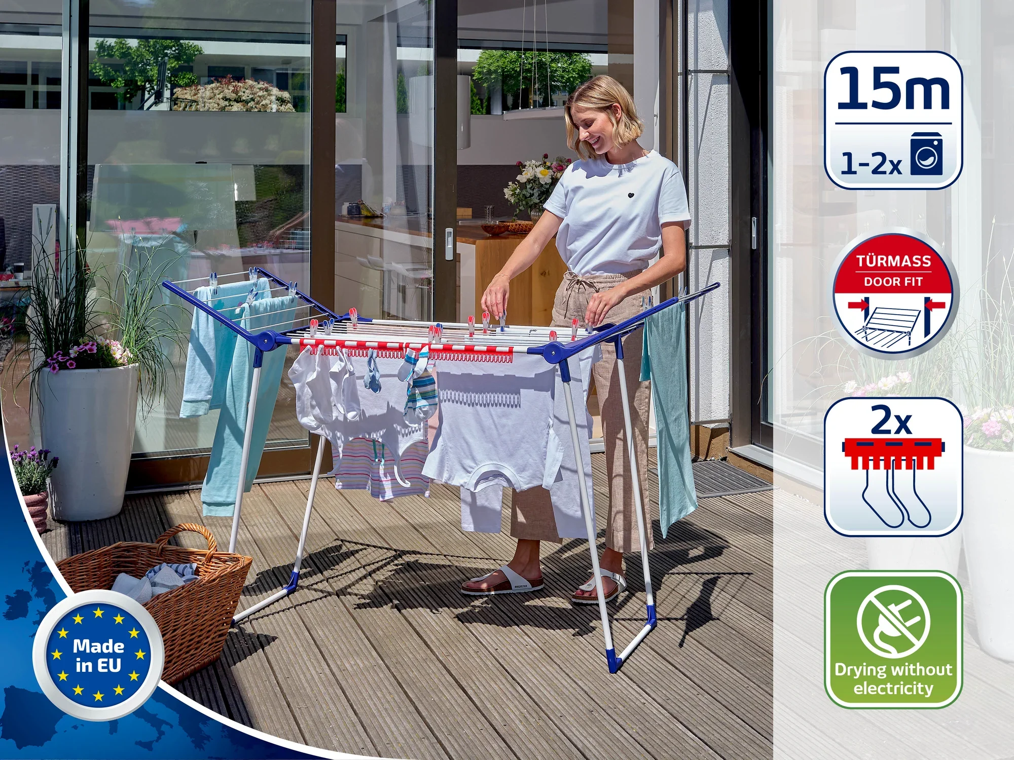 Eine Frau steht auf einer Terrasse und benutzt einen Standtrockner, um Kleidung zu trocknen. Der Trockner bietet Platz für bis zu 15 Meter Wäsche und benötigt keinen Strom.