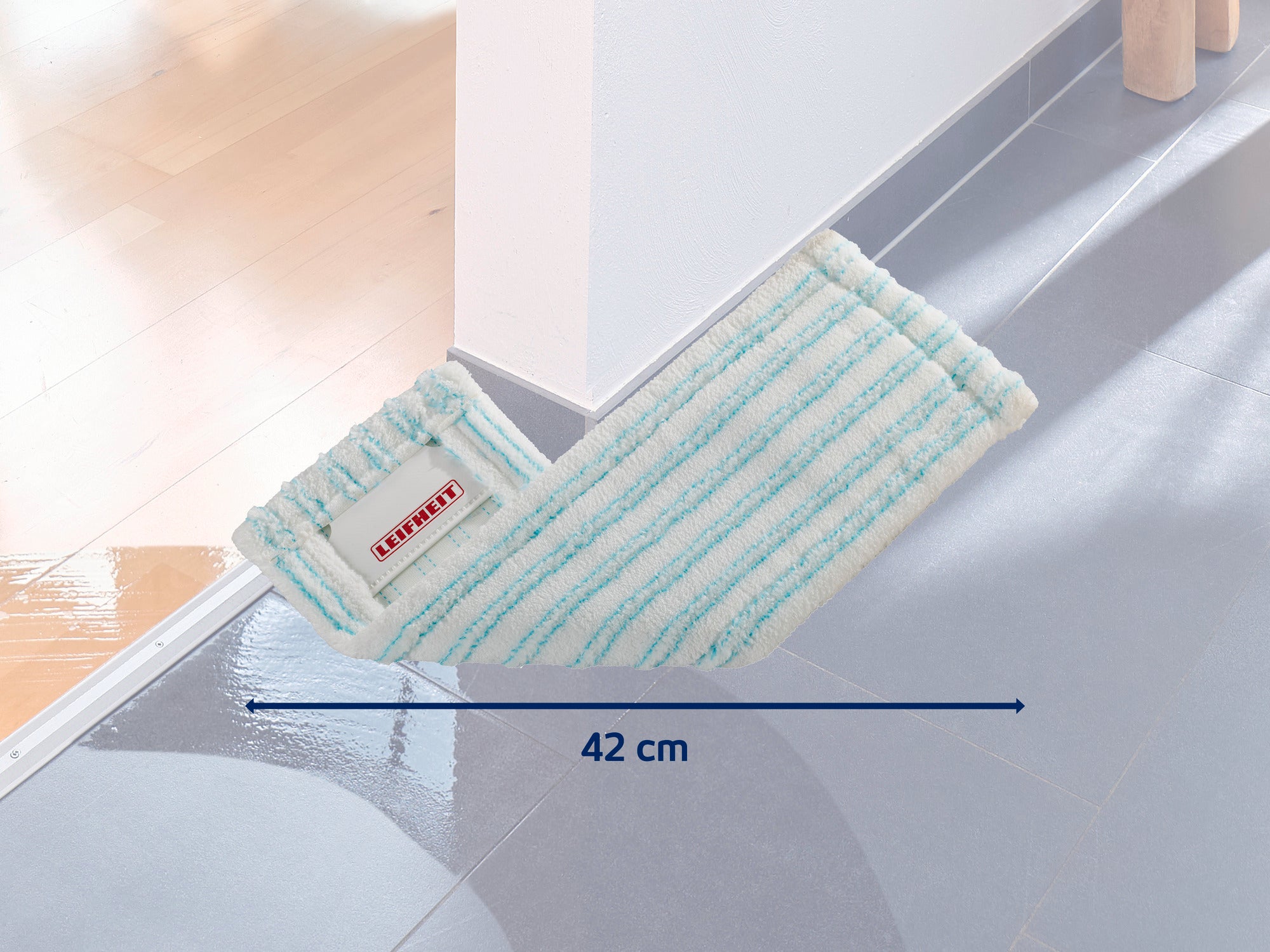 Ein Leifheit Wischbezug mit einer Breite von 42 cm liegt auf einem glänzenden, nassen Boden. Der Bezug hat hellblaue Streifen und ist ideal für die gründliche Reinigung.