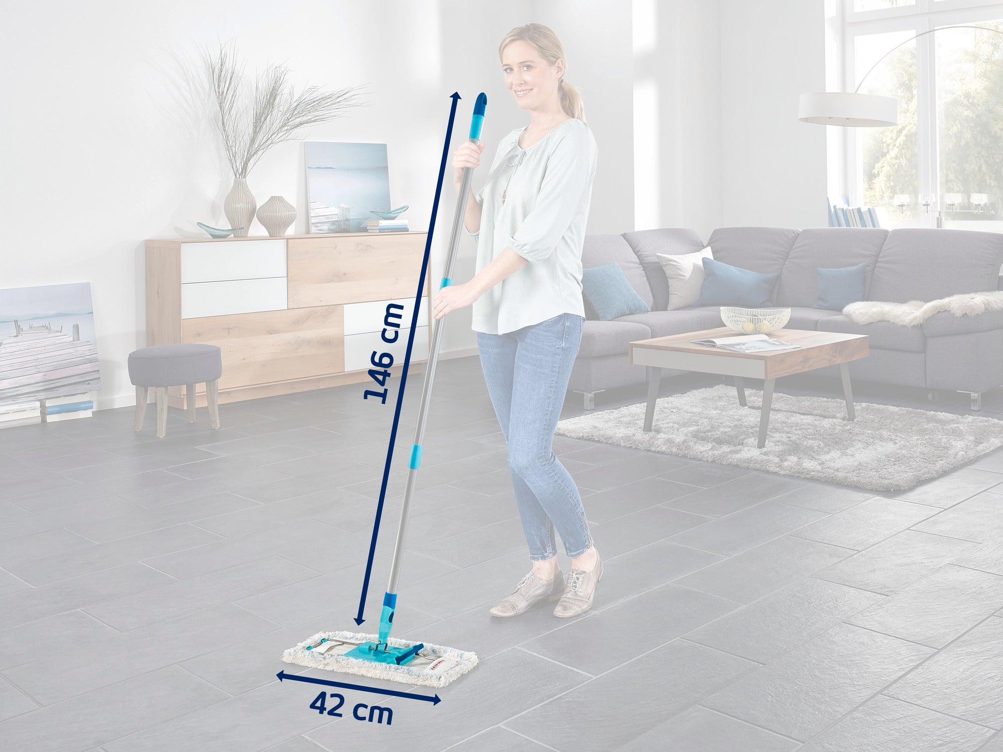 Kobieta używa mopa podłogowego z uchwytem o długości 146 cm i głowicą mopa o szerokości 42 cm w nowoczesnym salonie. Podłoga jest wyłożona kafelkami w ciemnym kolorze, a pokój jest stylowo urządzony.