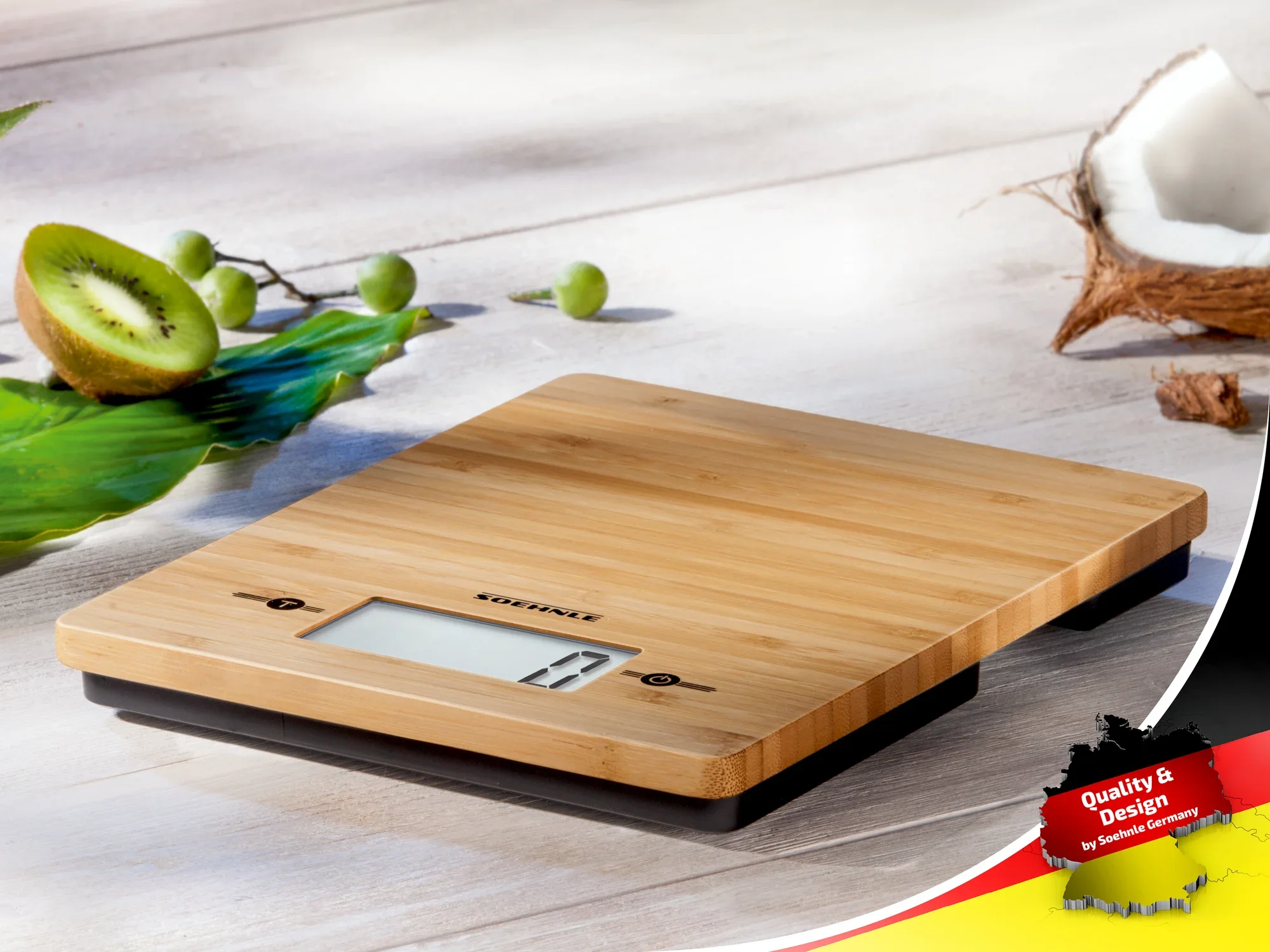 Digitale Küchenwaage aus Bambus mit LCD-Display auf einem Tisch, umgeben von frischem Obst wie Kiwi und Kokosnuss. Ideal für präzises Wiegen in der Küche.