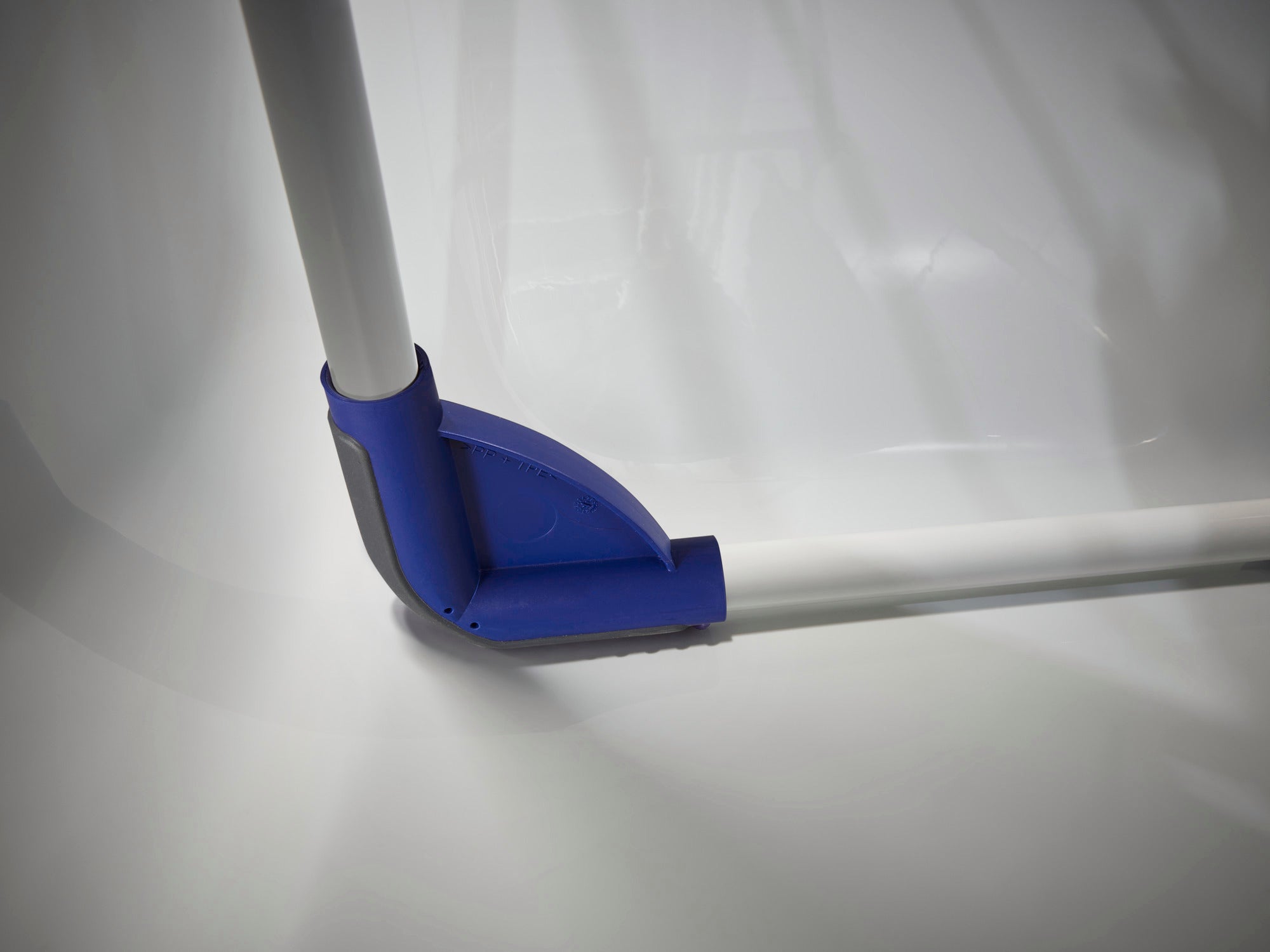 Hoek van een Pegasus 120 Solid Compact droogtrommel met blauw plastic scharnier. De wasdroger staat op een glad, wit oppervlak en laat de stevige constructie zien.