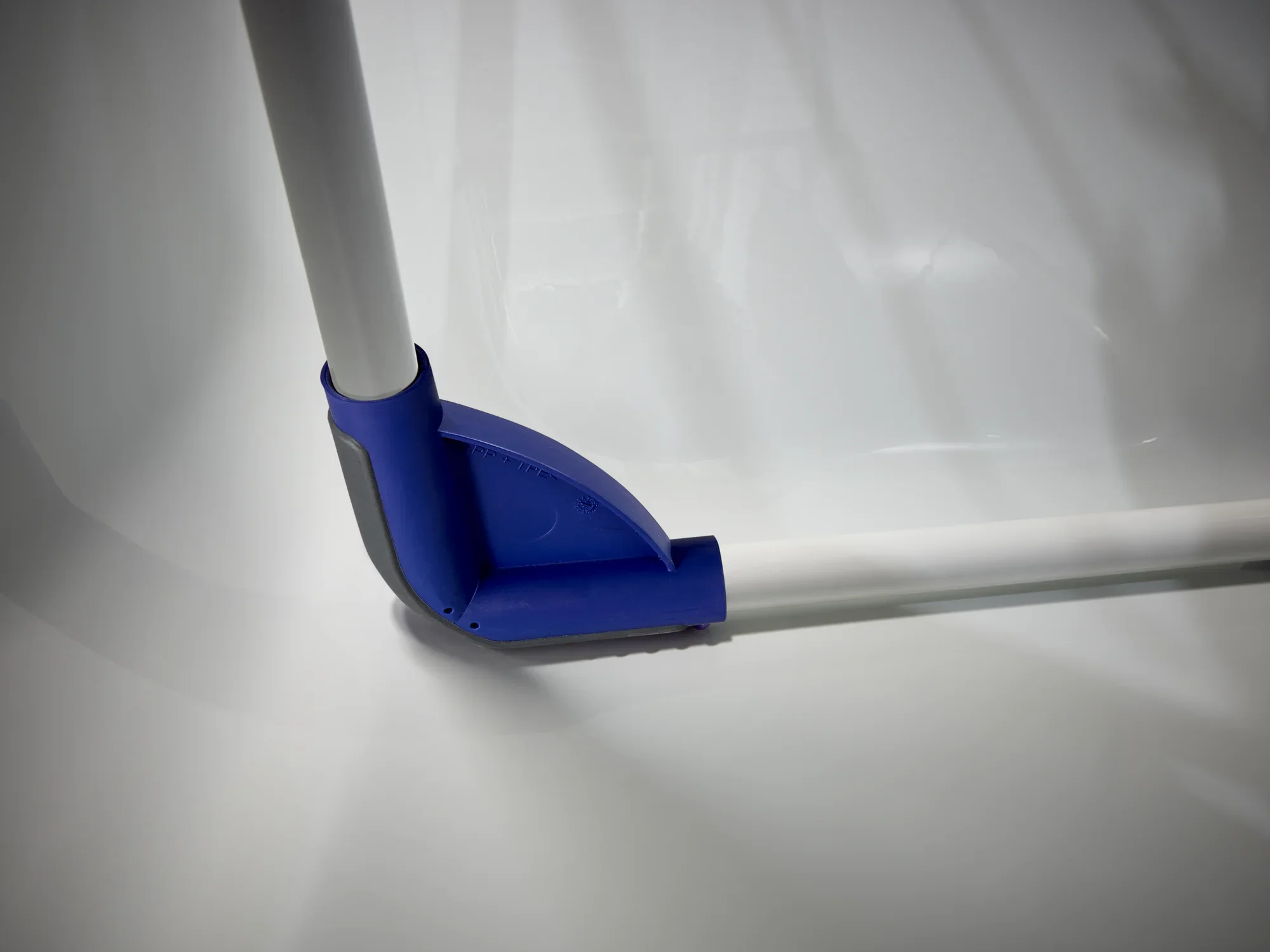 Narożnik suszarki bębnowej Pegasus 120 Solid Compact z niebieskim plastikowym zawiasem. Suszarka stoi na gładkiej, białej powierzchni i pokazuje swoją solidną konstrukcję.