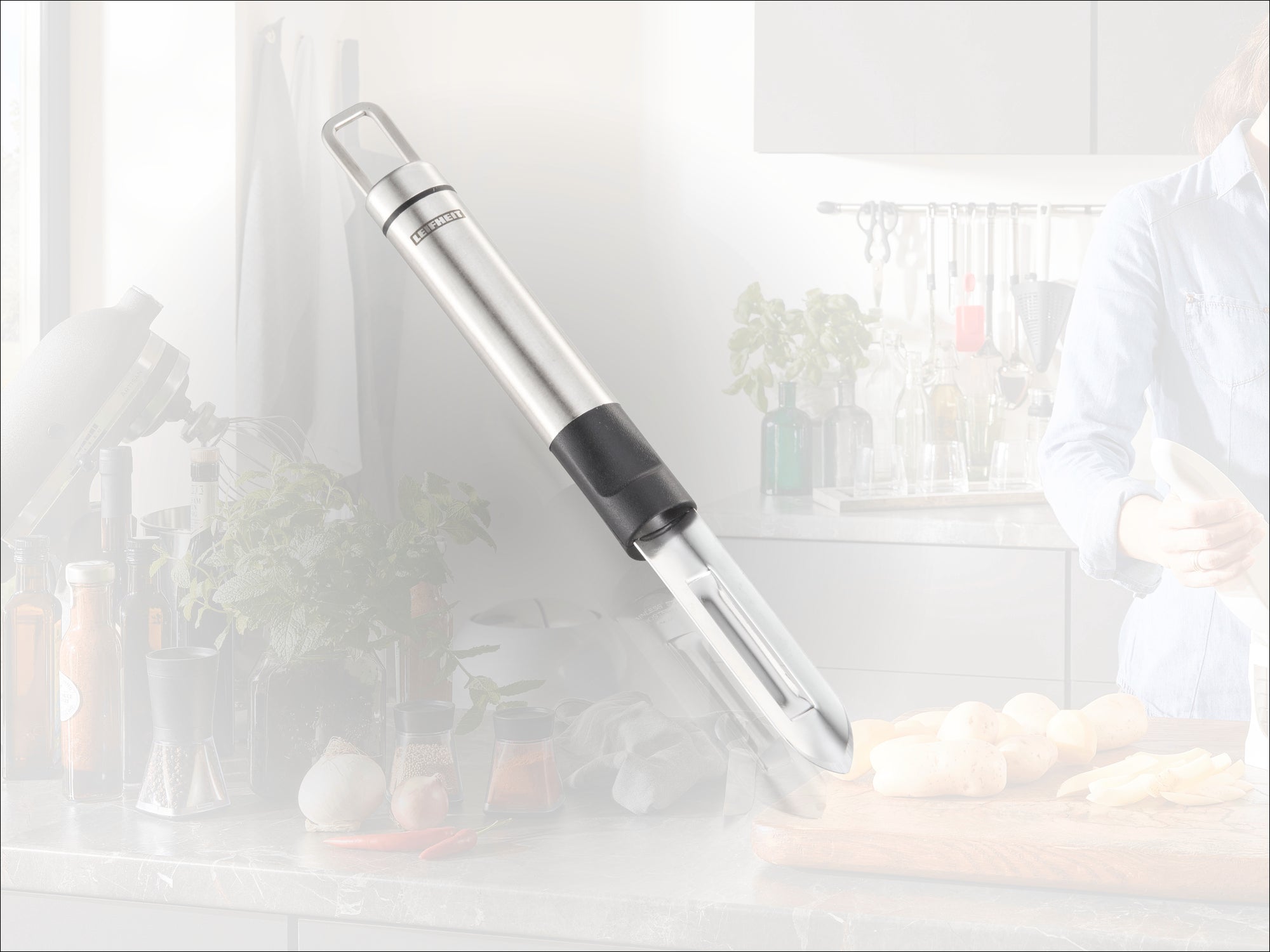Un éplucheur à légumes en acier inoxydable de haute qualité posé sur un plan de travail de cuisine. Des ustensiles de cuisine et des ingrédients frais sont visibles en arrière-plan. Idéal pour éplucher avec précision.