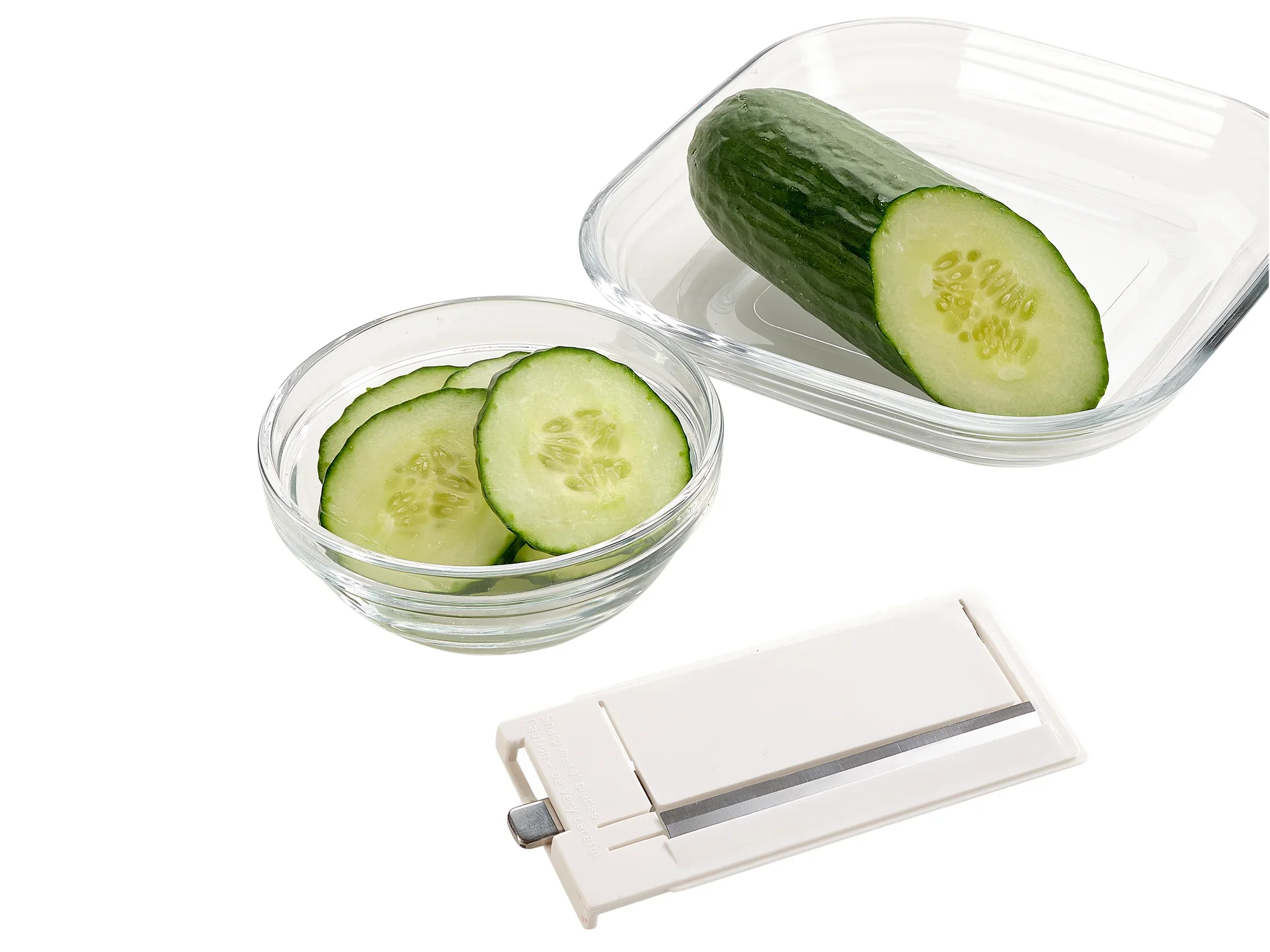 Een allesrasp met 4+1 toepassingen ligt naast een kom komkommerschijfjes en een halve komkommer. Ideaal om snel en precies groenten te snijden.