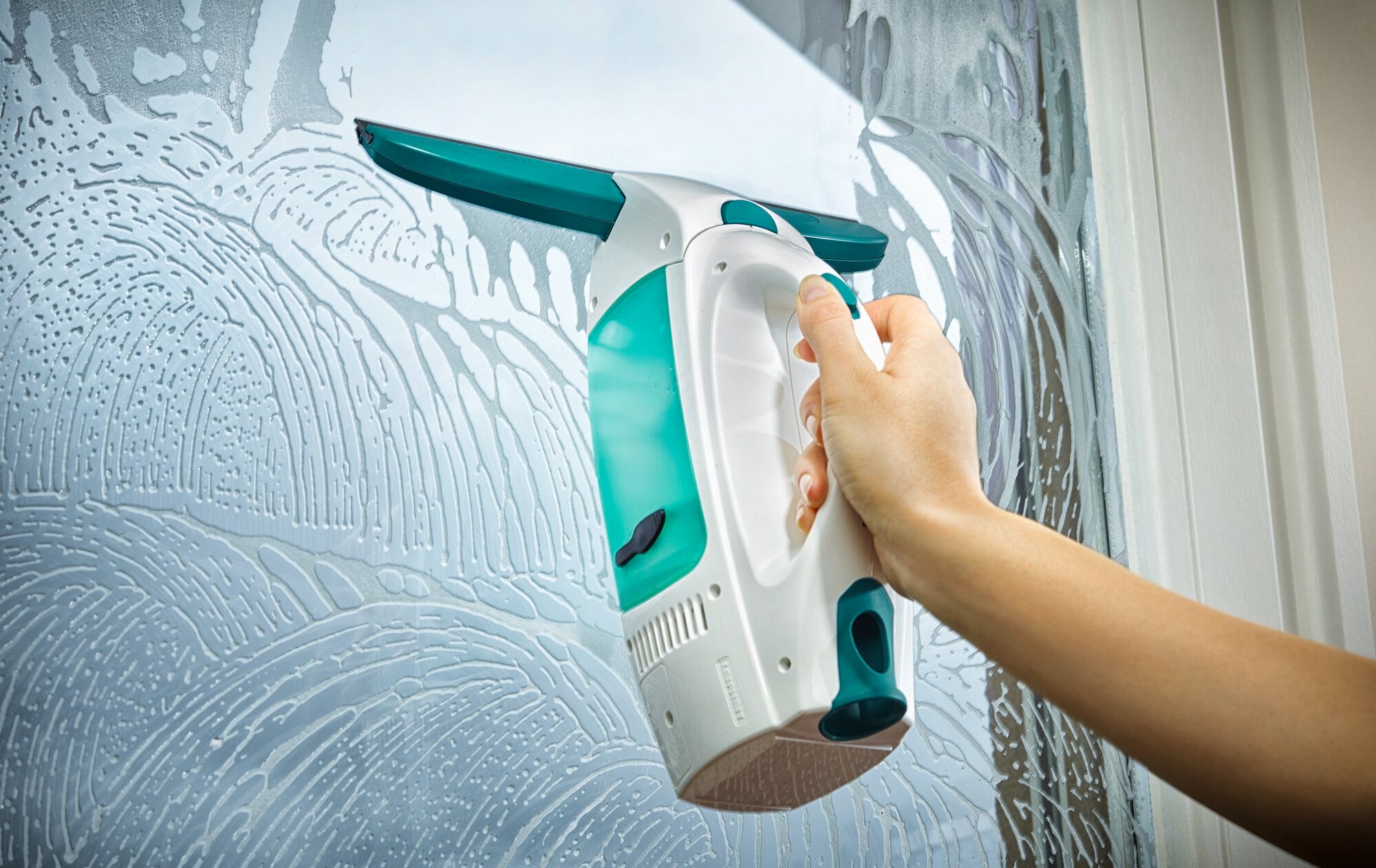 Ein Fenstersauger Dry and Clean wird verwendet, um ein Fenster zu reinigen. Die Hand hält das Gerät, während es über die nasse Glasoberfläche gleitet und Wasser entfernt.