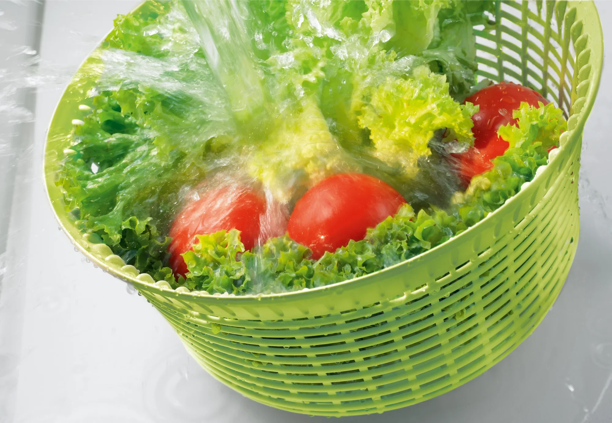 Wirówka do sałaty 5,5 l w akcji: Świeża sałata i pomidory są myte w zielonym koszu z wodą. Idealny do szybkiego i wydajnego suszenia sałaty.