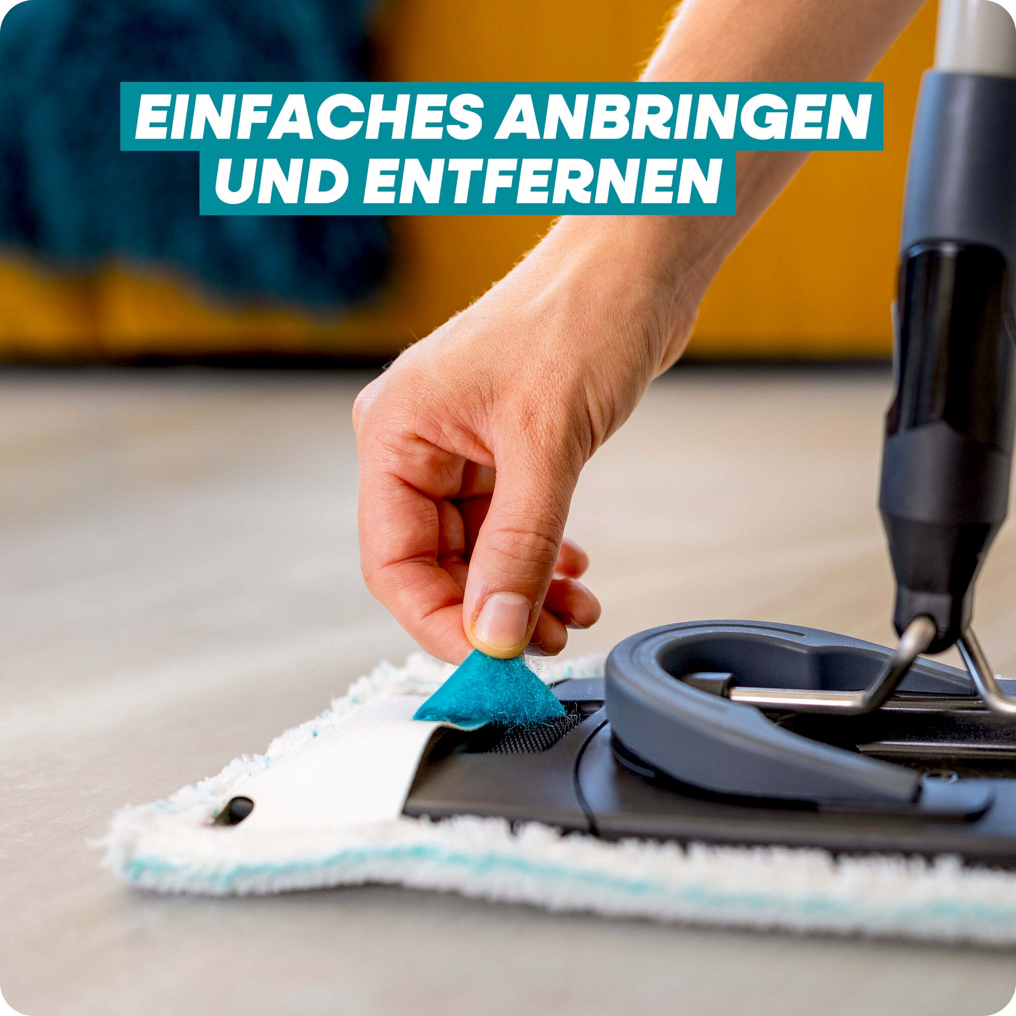 Leifheit Set CLEAN TWIST M Black: Eine Hand befestigt oder löst den Wischbezug am flachen Bodenwischer per Lasche; Nahaufnahme des Systems auf hellem Boden, mit Hinweis auf einfaches Anbringen und Entfernen.