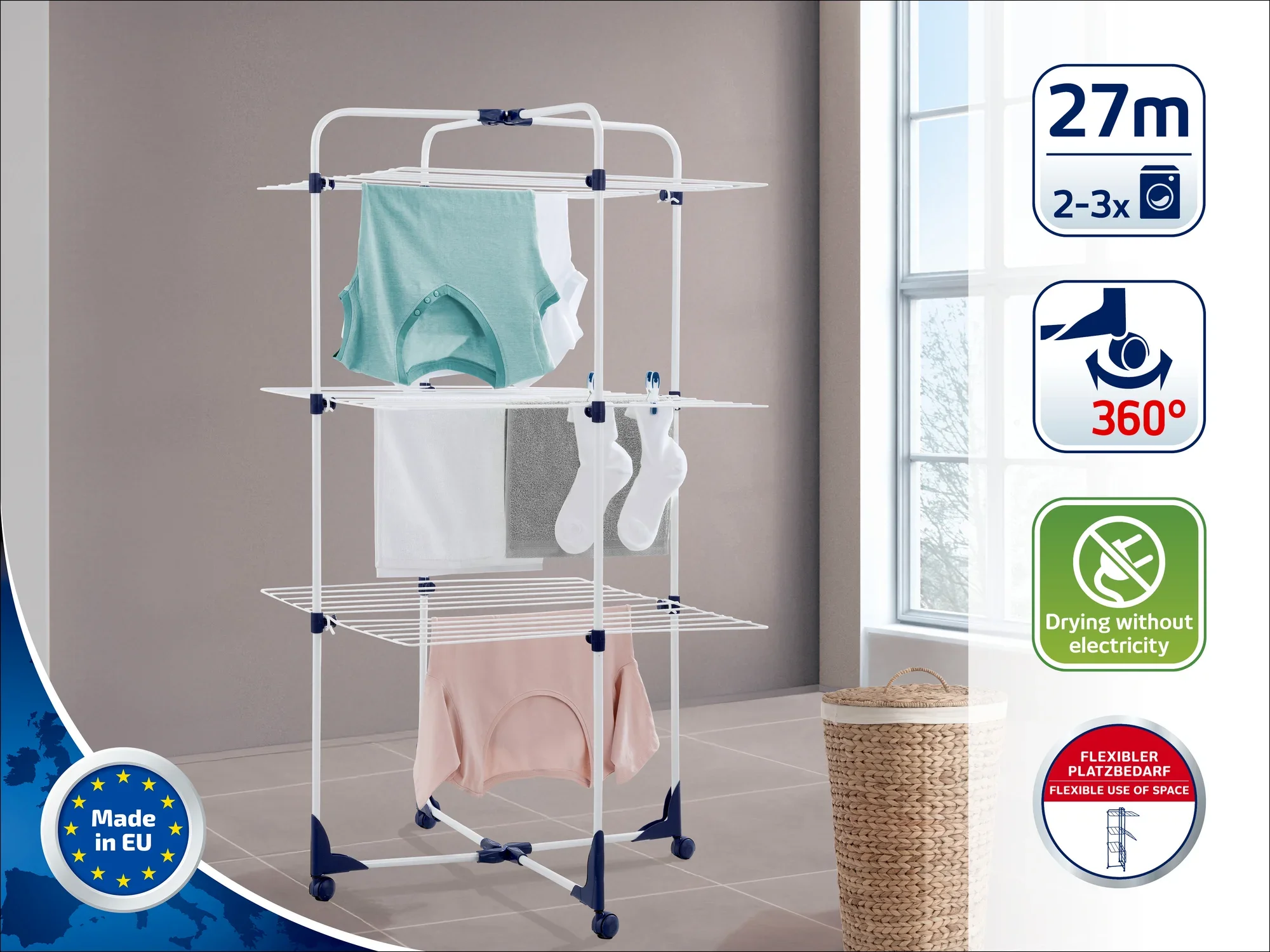 Een torendroger staat in een lichte kamer. Hij heeft verschillende niveaus voor het drogen van kleding. De labels geven een drooglengte aan van 27 meter, 360° rotatie en geen stroomverbruik.