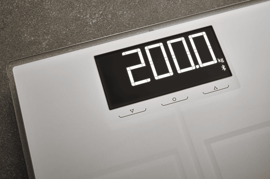 Elektronische Waage mit weissem Gehaeuse zeigt 200 kg auf einer digitalen Anzeige auf einem grauen Boden.