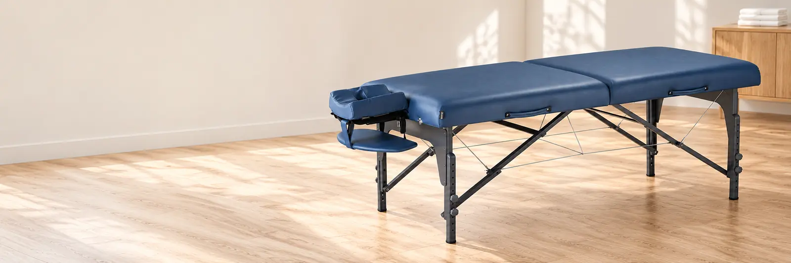 Blue portable massage table shown in a bright treatment room