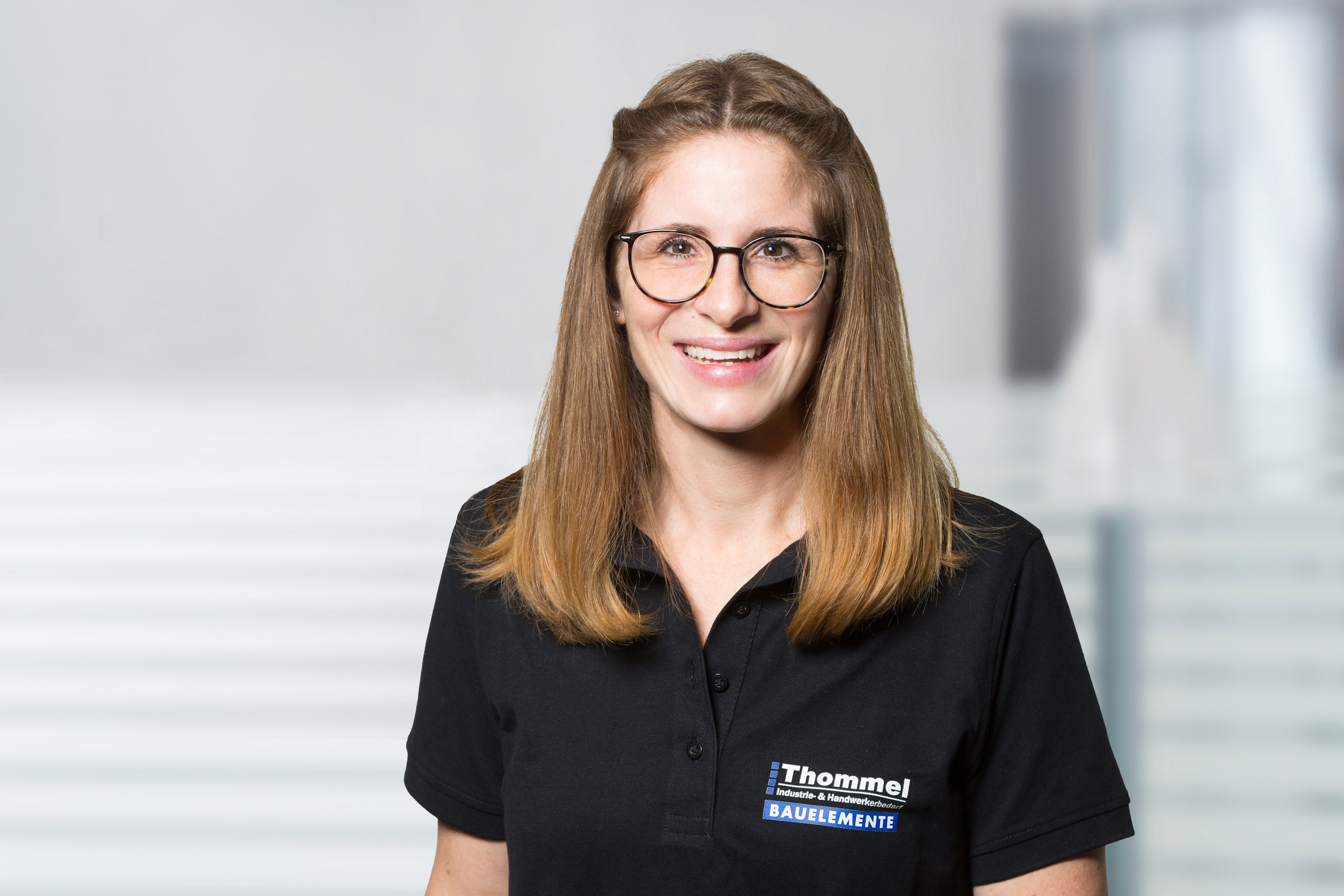 brille, frau, schwarzes polohemd, shirt mit logo, porträt indoor