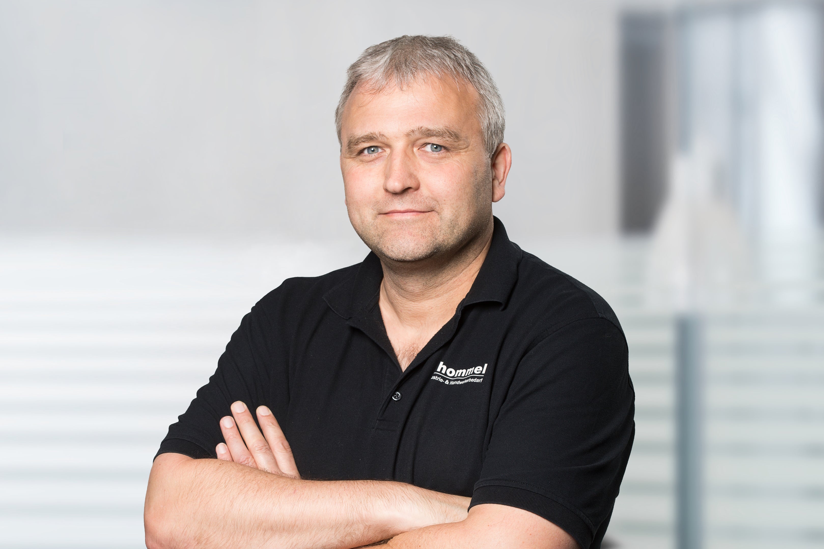 portrait, mann, schwarz polo, kurze haare, arme verschränkt