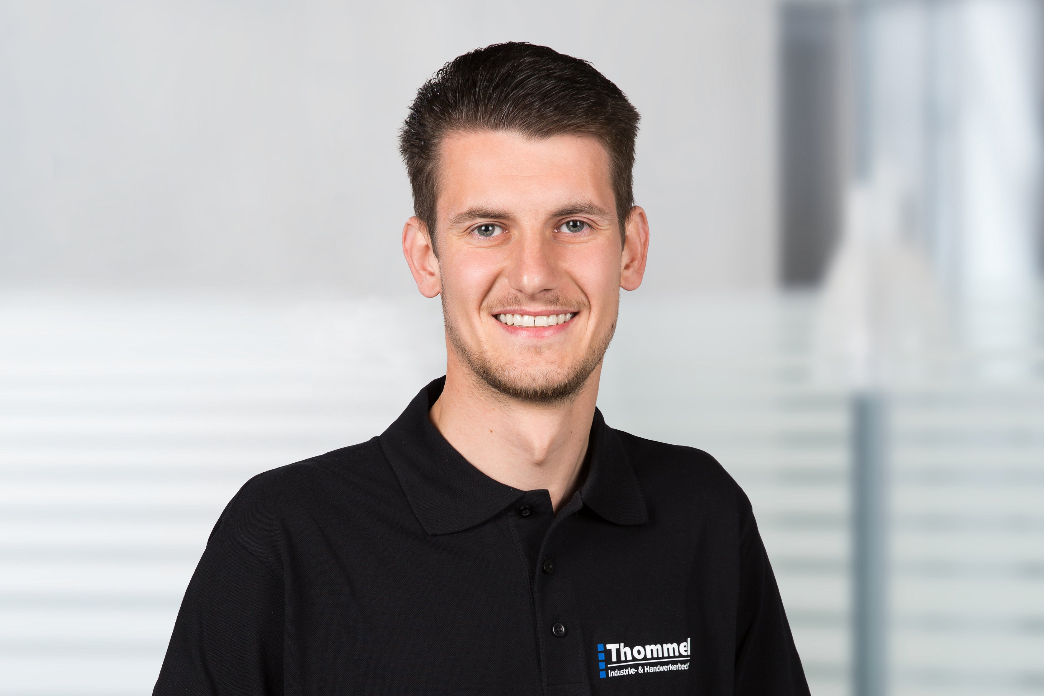 man, schwarzes polohemd, kurze haare, lächeln, mitarbeiter