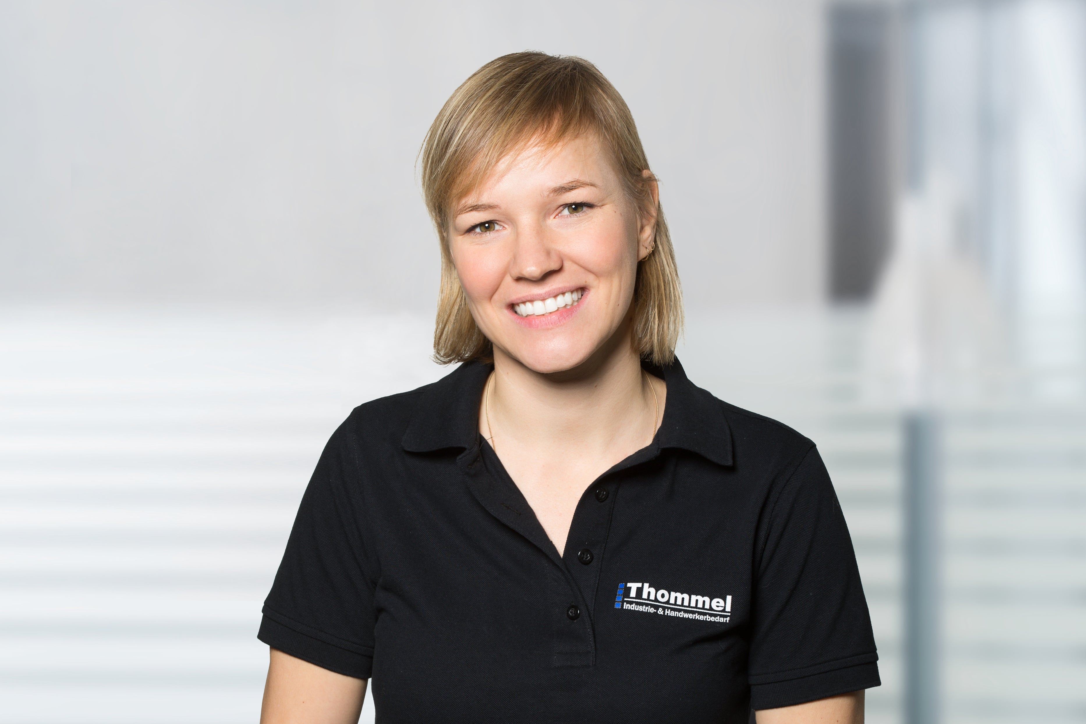Frau, schwarzes Polohemd, Logo, blondes Haar, Lächeln