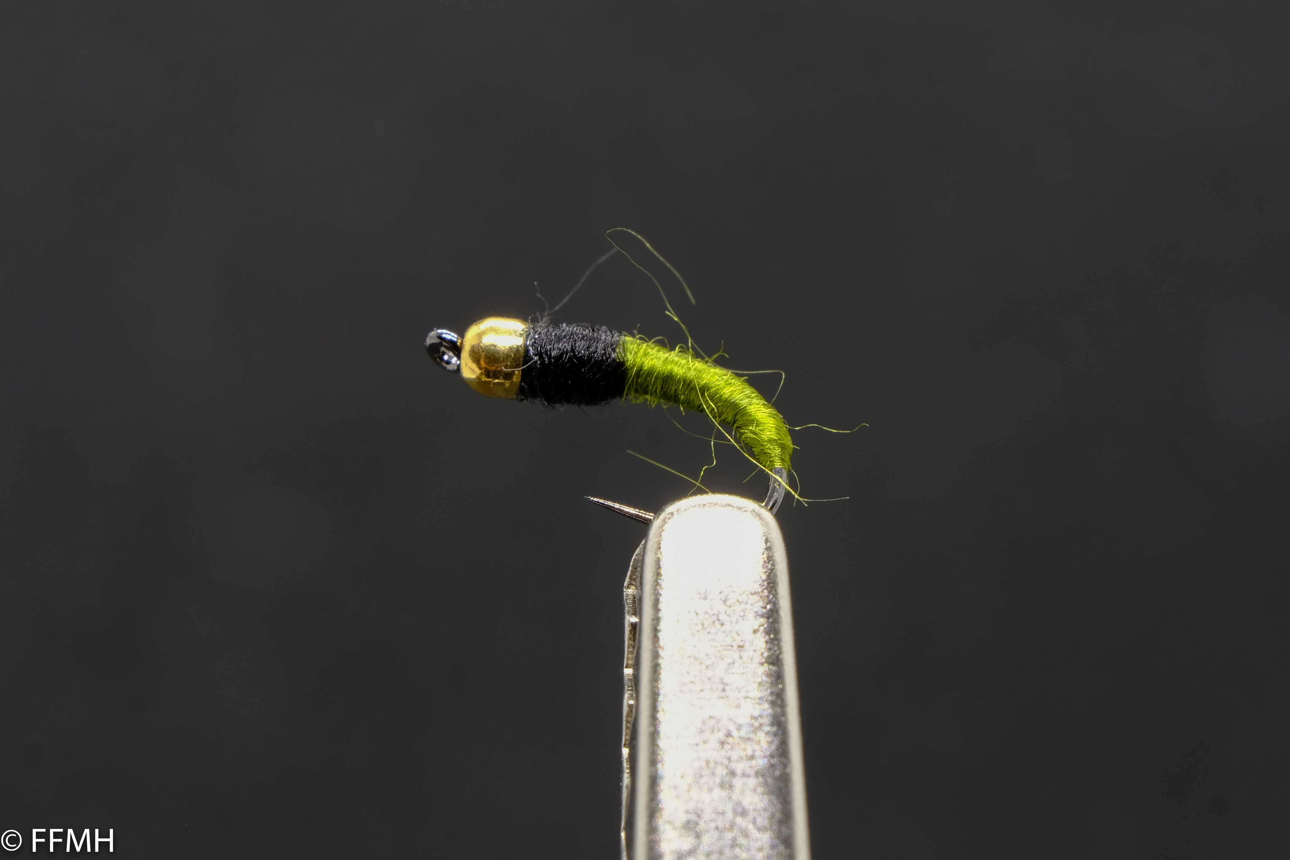 Gold Head Black Green Body – kraftvolle Nymphe mit auffälligem Farbkontrast Gold Head Black Green Body – handgebundene Nymphe mit glänzendem Goldkopf, schwarzem Brustbereich und signalgrünem Körper, liebevoll gestaltet für effektives Fliegenfischen in bewegtem Wasser